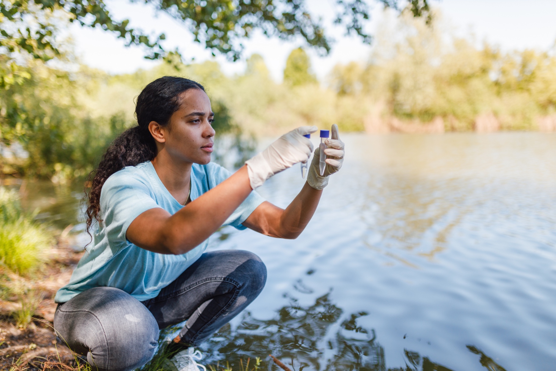 A lake field technician on a boat holding a labeled water sample bottle