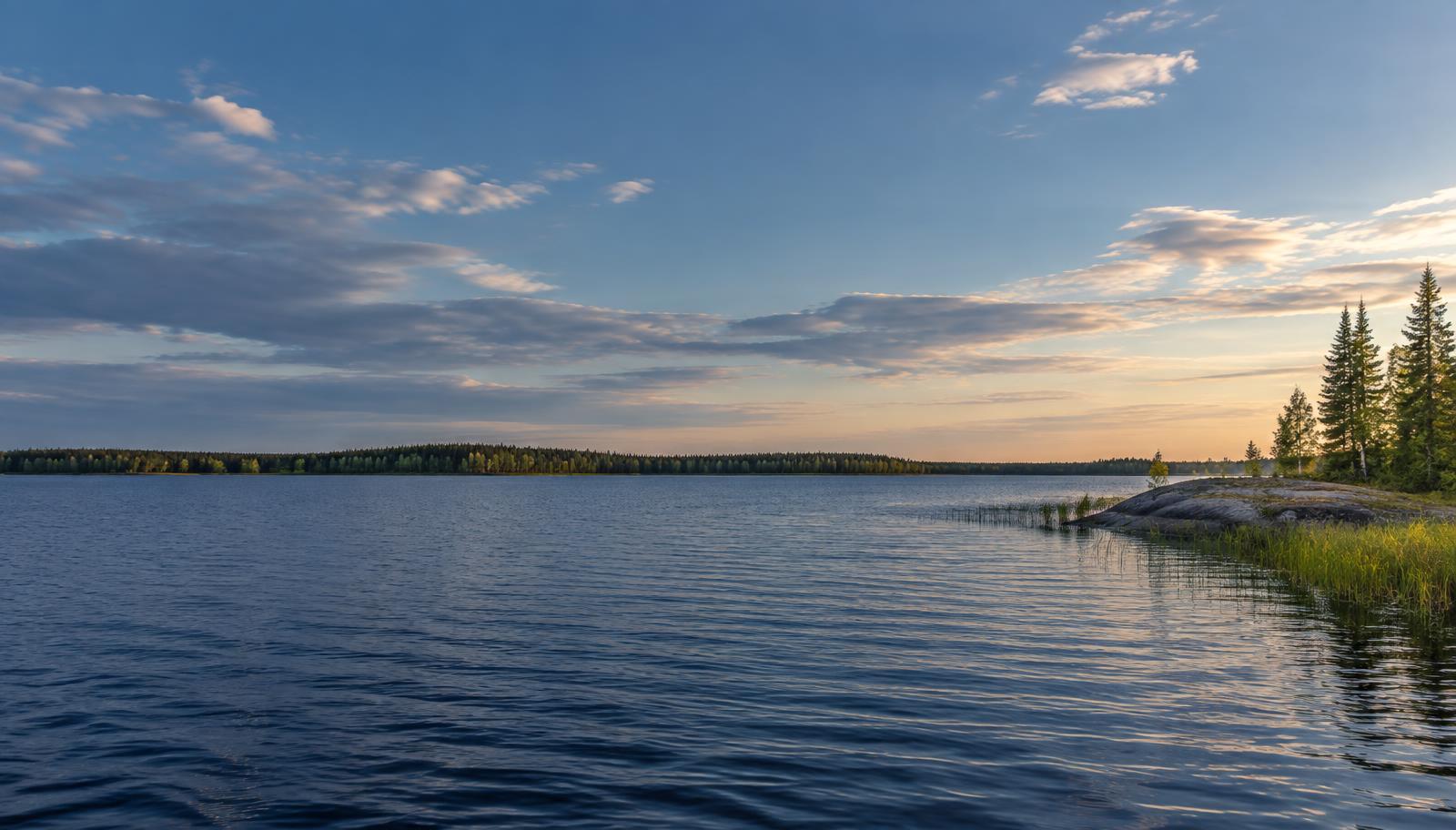 A broad north-woods lake beneath open clouds