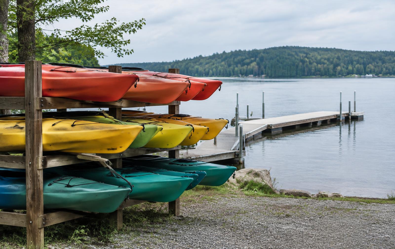Rental kayaks racked at a small lake marina beside a dock